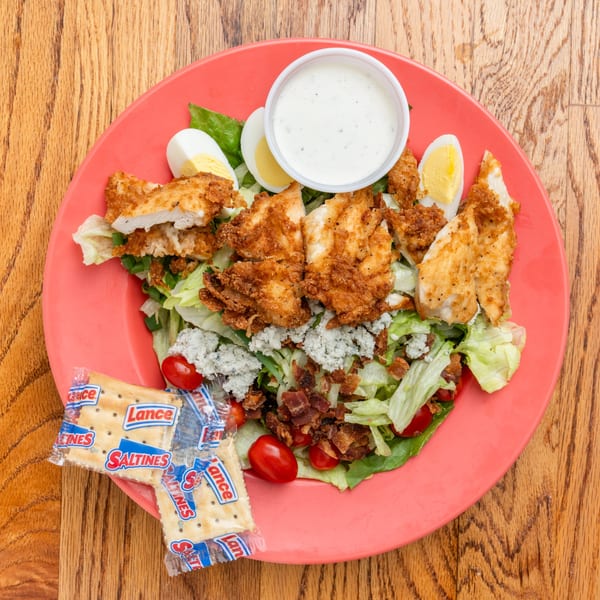 Southern fried chicken salad with bacon, blue cheese, tomatoes, hard-boiled eggs, and ranch dressing.