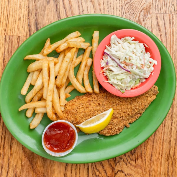 Southern fried fish with french fries, coleslaw, ketchup, and a lemon wedge on a green plate.