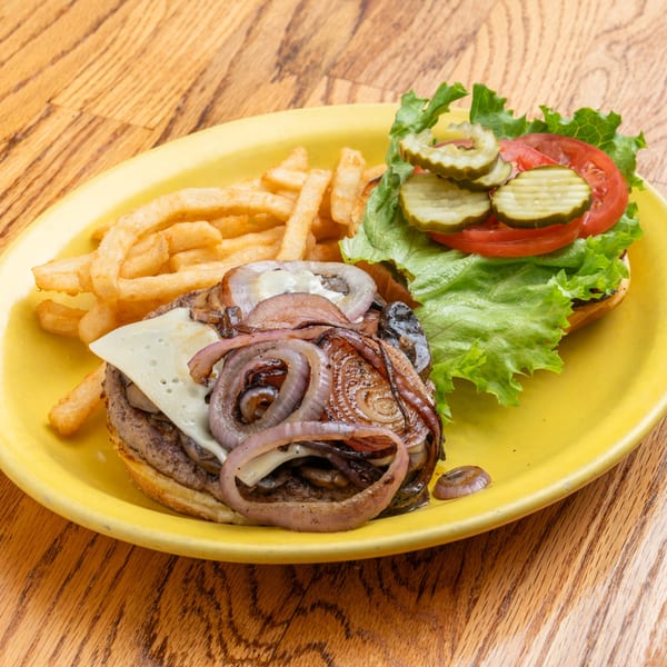 A Southern-style burger with caramelized onions, cheese, lettuce, tomato, and pickles, served with fries.